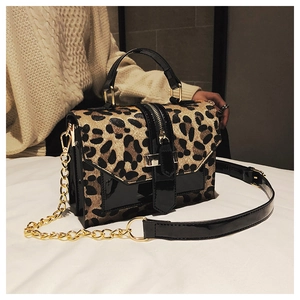 Detail of leopard print crossbody bag with glossy black trim and gold chain strap