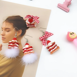 Detail of strawberry cake earrings with red plaid bow and white faux fur pompom