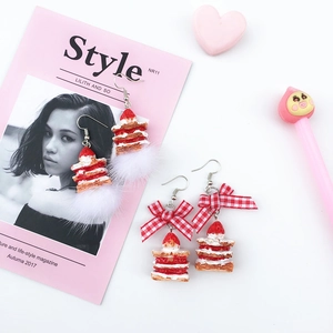 Detail view of strawberry cake earrings with mink fur pom-poms and plaid bow ribbons