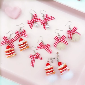 Detailed flat lay of cute strawberry cake earrings and plaid bows on a pink tray