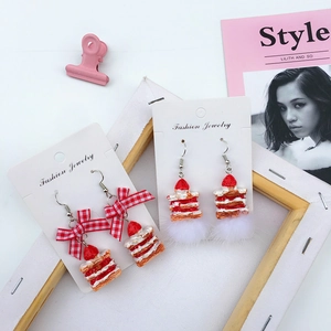 Detail of strawberry cake earrings with red plaid bow and white faux fur pom poms
