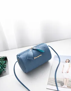 Blue mini pillow bag with litchi grain texture and bow zipper detail on white table