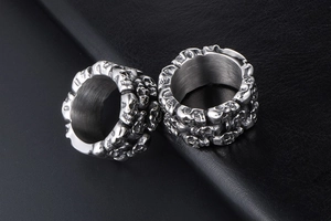 Macro shot of two silver skull rings in titanium steel with detailed 3D carving