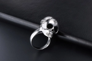Macro shot of silver vintage skull ring featuring cross detail on high-polish steel surface