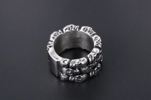 Close-up of silver titanium steel ring featuring multiple 3D embossed skulls