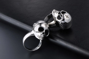 Detailed macro shot of two silver skull rings on a dark textured leather background