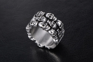 Macro detail of men's titanium steel ring featuring multiple embossed skull reliefs