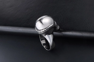 Detailed view of silver skull ring with woven side texture on black leather surface