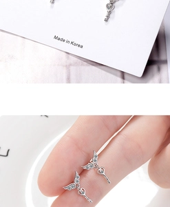 Detailed macro view of silver angel wing and heart key earrings with sparkling crystal accents