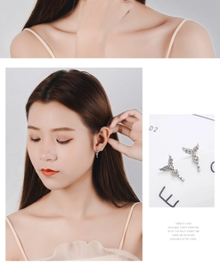 Detail of silver angel wing key earrings with heart-shaped zircon stones on model