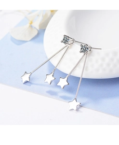 Silver star drop earrings with sparkling cubic zirconia on a white decorative bowl
