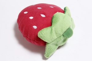 Detailed close-up of a red plush strawberry pet toy with green leaves on white background