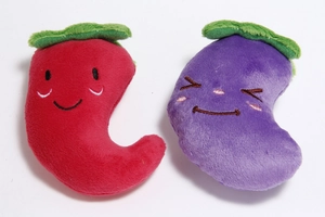 Close-up of plush dog toys in red pepper and purple eggplant shapes with embroidery
