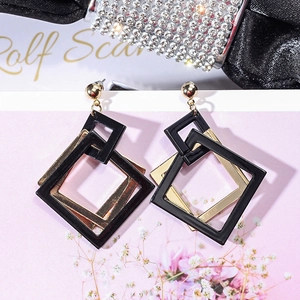 Detail of geometric acrylic drop earrings featuring black and gold double-layered squares