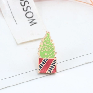 Detail view of green enamel plant brooch with decorative Blossom tag on white background
