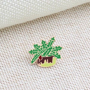 Detailed close-up of a green potted plant enamel brooch with golden metal outlines