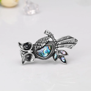 Detailed macro view of vintage owl brooch with natural abalone shell and black rhinestone eyes