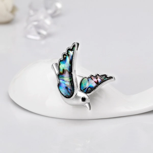 Macro shot of bird brooch featuring natural abalone shell wings on silver metal