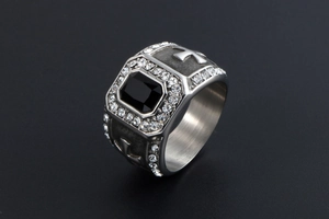 Vue macro de bague argentée avec pierre noire carrée et gravure de croix