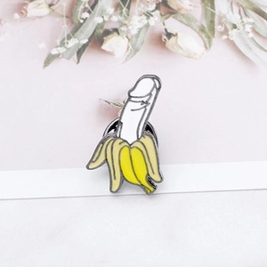 Detail of banana-shaped enamel pin with funny anatomical inner design and metal backing