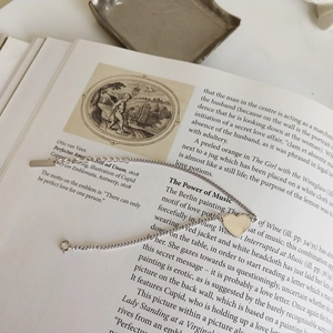 Detail of 925 sterling silver heart bracelet on vintage book page with spring clasp