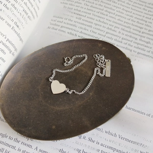 Macro view of a 925 sterling silver heart pendant bracelet with an S925 engraved tag