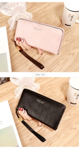 Detailed comparison of pink and black leather wallets with wristlets on wooden surface