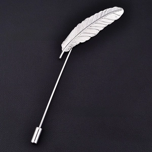 Macro shot of silver alloy feather brooch with detailed texture on black leather surface