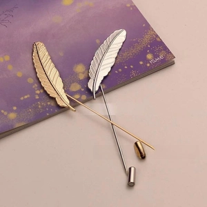 Detail of silver and gold feather lapel pins showing brushed metal texture and pin caps