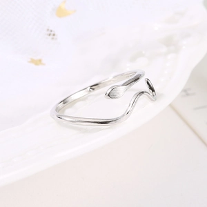 Detail shot of a silver serpent ring with wave patterns on a white porcelain dish