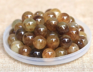 Macro shot of polished natural golden rutilated quartz beads with internal needle inclusions