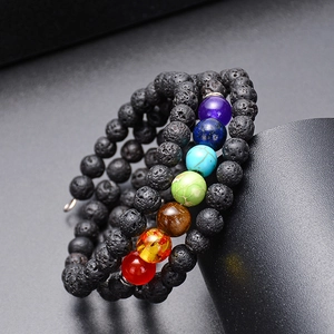 Détail du bracelet multicouche en pierre de lave avec sept perles chakra sur fond noir