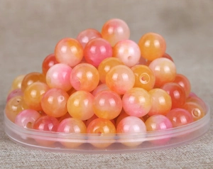 Makro-Detail von runden Natursteinperlen mit pink-orangefarbenem Farbverlauf für DIY-Schmuck