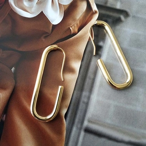 Detailed view of elegant gold-plated geometric oval hoop earrings on a fashion magazine