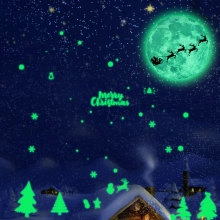 Luminous Christmas window stickers showing glowing Santa, moon, and stars at night