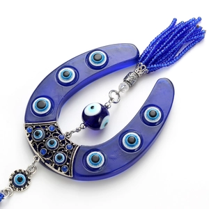 Detail of blue glass horseshoe evil eye hanging ornament with elegant beaded tassel