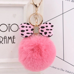 Close-up of fluffy pink faux fur pompom keychain with leopard print bow and sparkling rhinestone