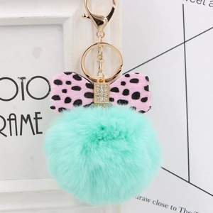 Detail of mint green plush pom pom keychain with leopard bow and gold hardware
