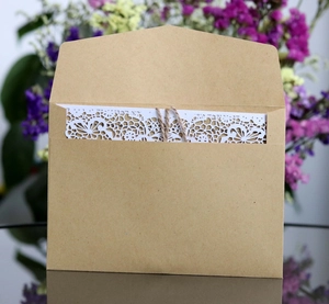 Detail of laser-cut lace invitation card inside a brown kraft paper envelope