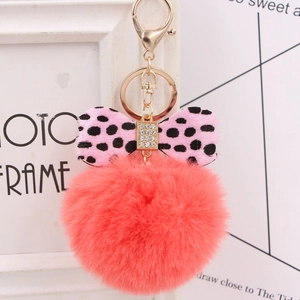 Close-up of pink faux fur keychain with polka dot bow and rhinestone details