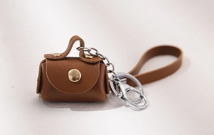 Detailed macro of brown lychee grain leather mini coin purse keychain with gold button