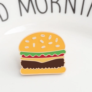 Detailed view of multilayered hamburger enamel pin showing sesame seeds and lettuce textures