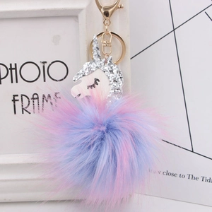Detail of colorful faux fur pompom keychain with white glitter unicorn head and gold clip