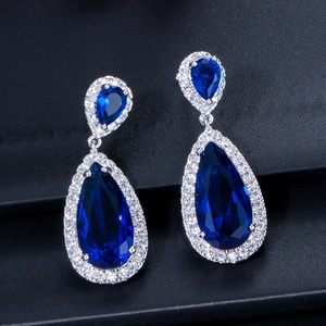 Macro view of teardrop halo earrings with deep blue gemstones and white zircon pave