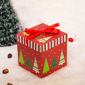 Detail einer roten Weihnachtsgeschenkbox mit Schleife und Baum-Motiven auf flauschigem Grund