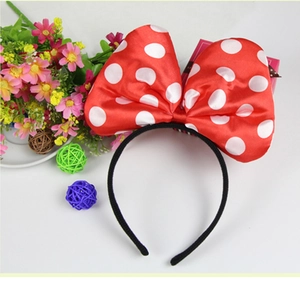 Close-up of a large red and white polka dot bow headband on a white background