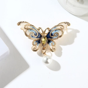 Gros plan détaillé d'une broche papillon en émail bleu avec strass et perle suspendue
