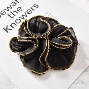 Detail of black scrunchie with golden wavy edge and textured fabric on magazine
