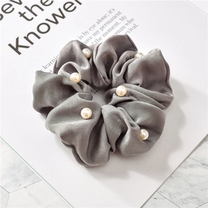 Detailed view of grey satin scrunchie with faux pearl accents on a display card