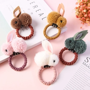 Close-up of five colorful plush bunny hair ties with handmade tags on pink background